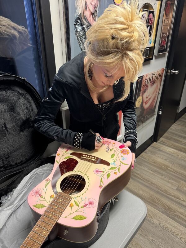 Dolly Parton signing custom guitar